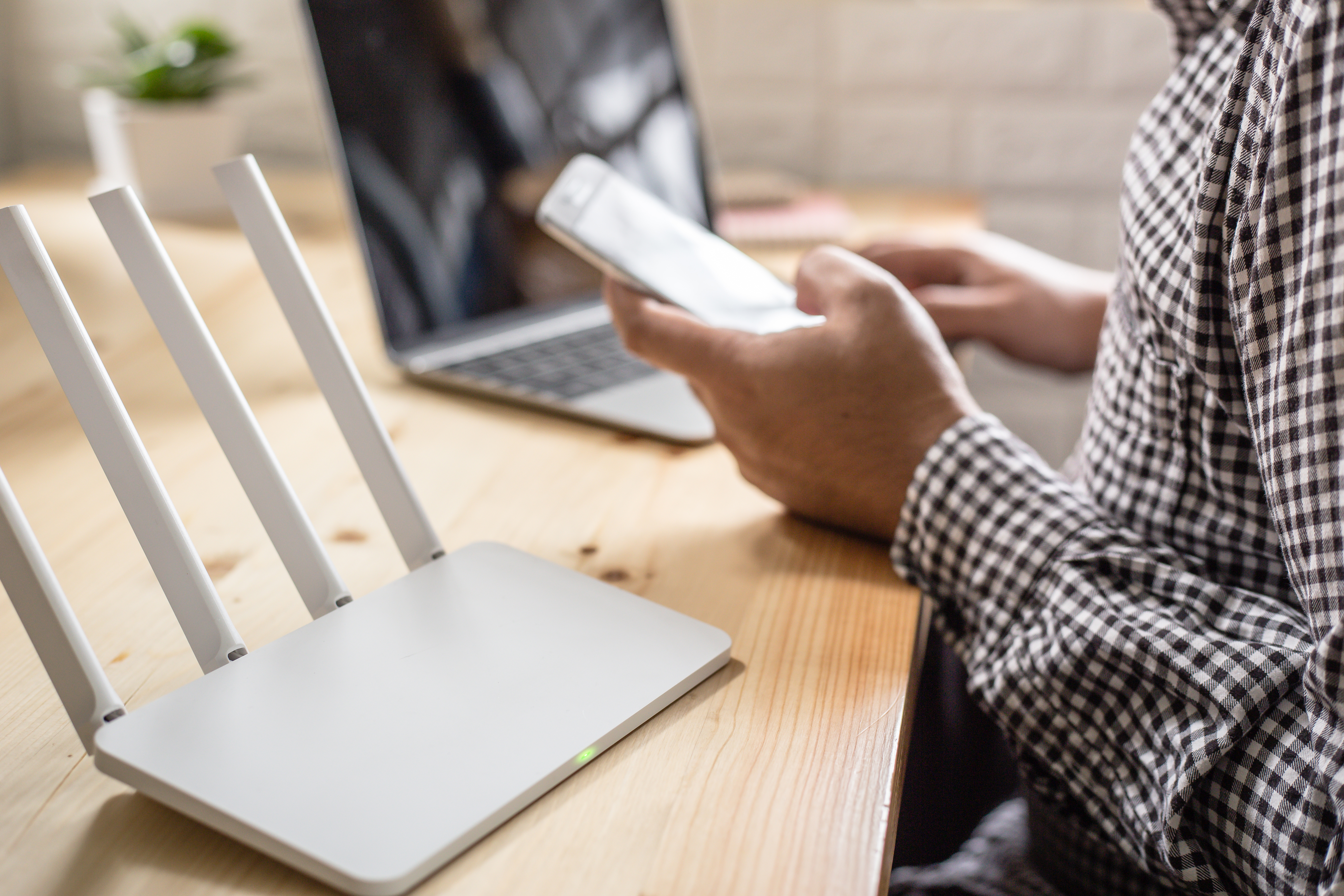 closeup of a wireless router and a man using smartphone on living room at home ofiice